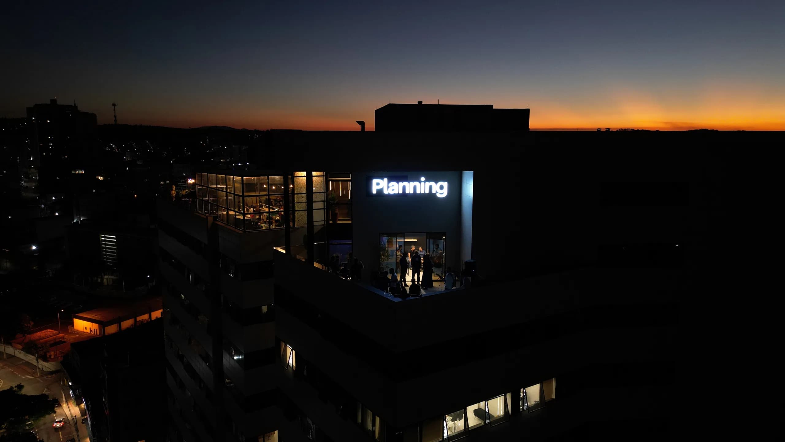 Sede da Planning com letreiro iluminado ao entardecer